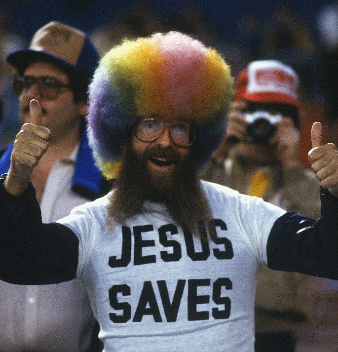 Rollen at a game with a rainbow afro styled wig and a jesus saves t shirt