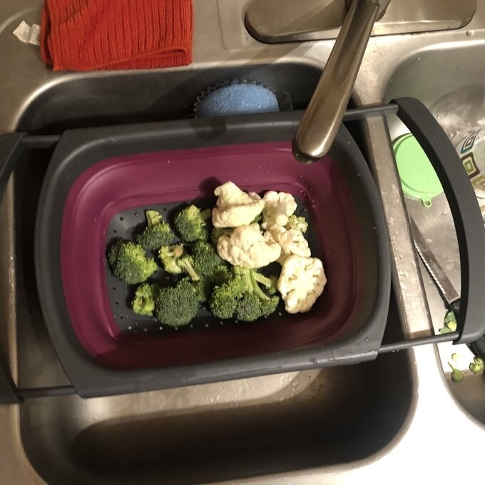 The strainer over the sink with broccoli and cauliflower