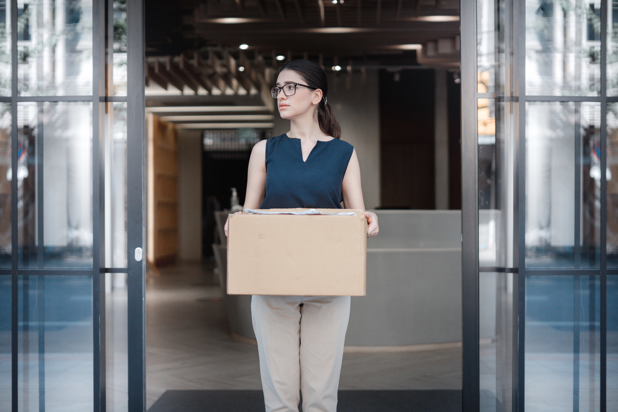 A woman walking out of a building holding a cardboard box