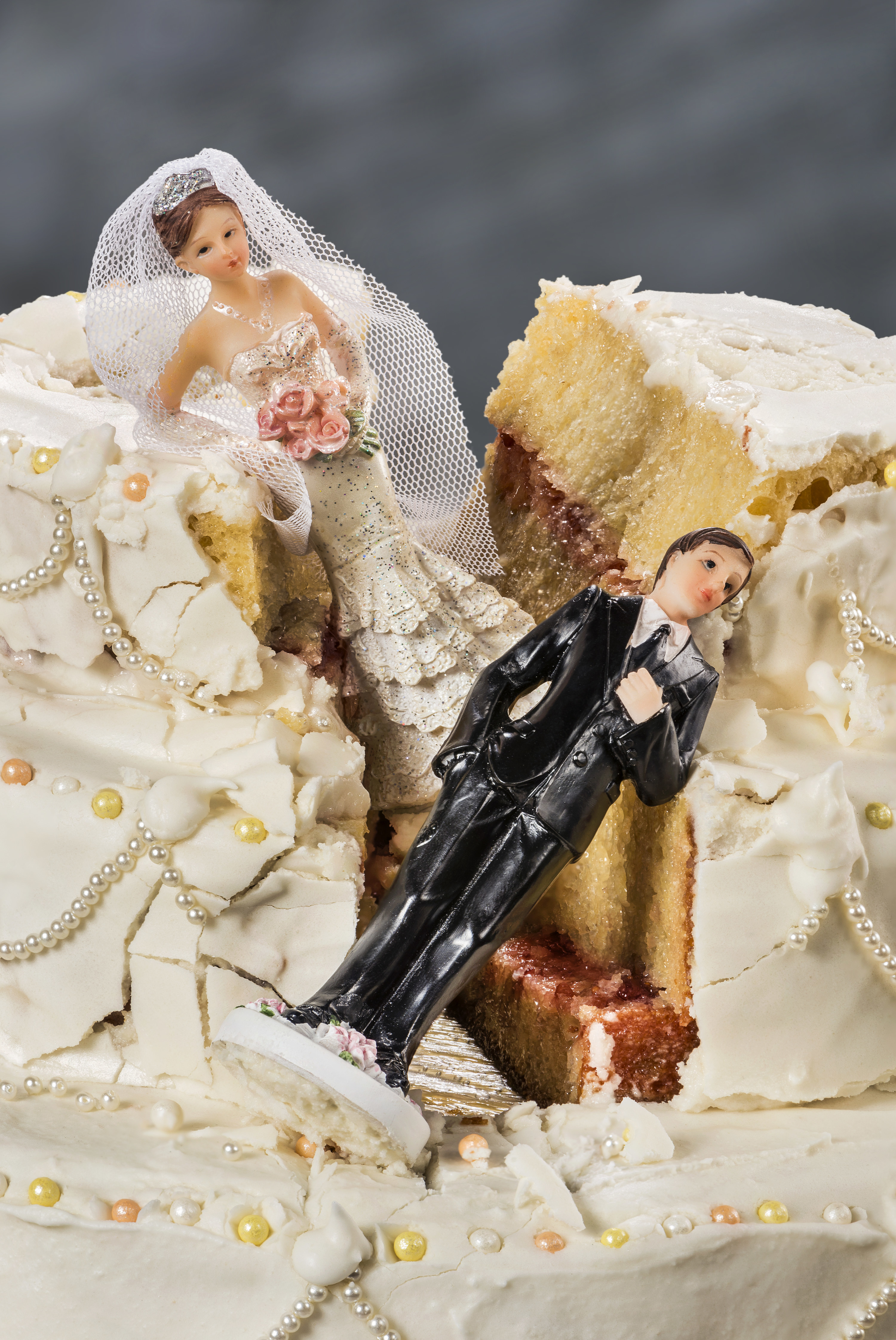 The top of a wedding cake that has been smashed with the bride and groom toppers sliding down the side