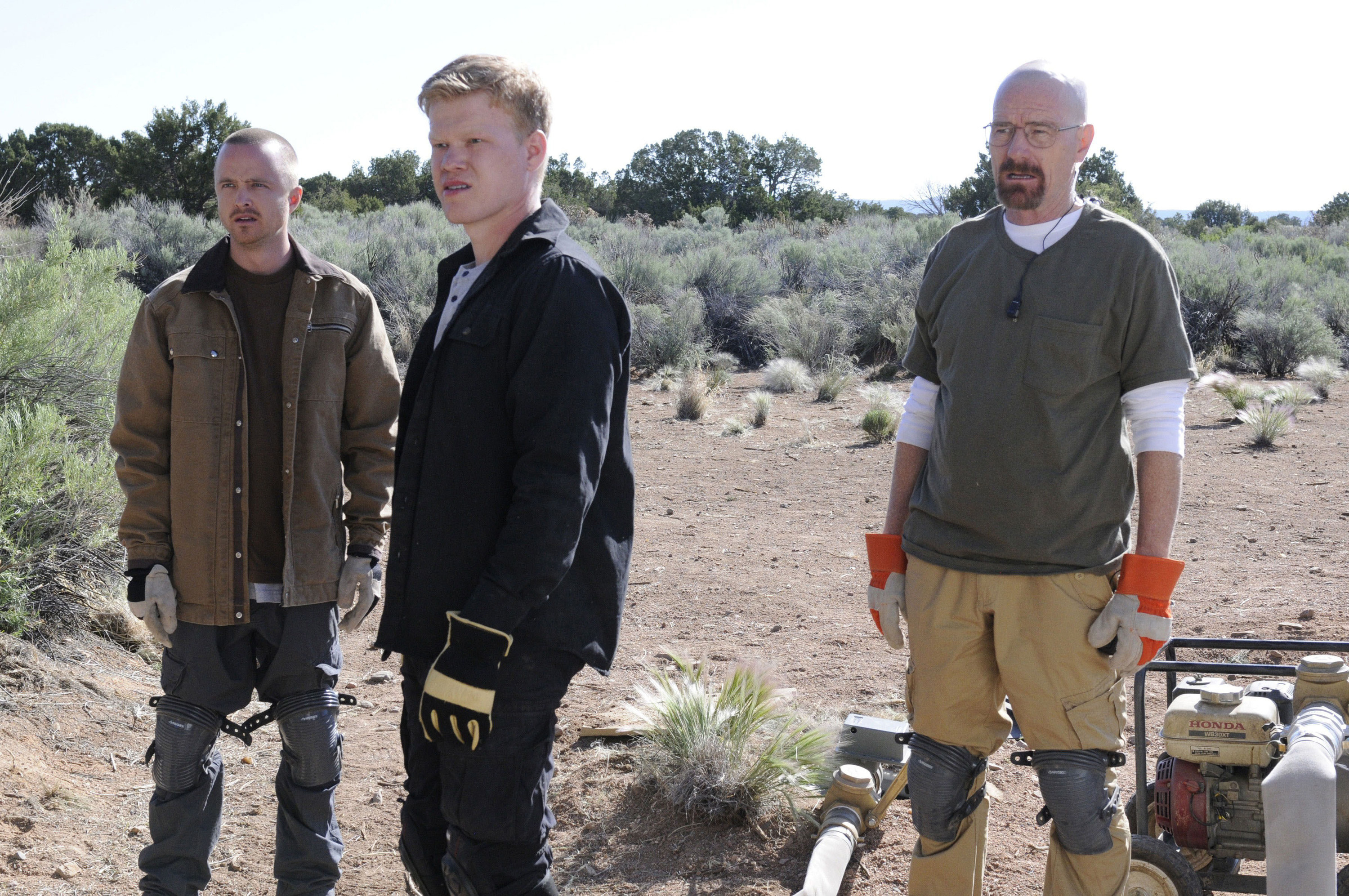 Jesse, Walter, and Todd from Breaking Bad stand at a desert construction site