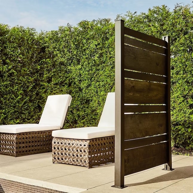a wood and steel privacy screen in front of patio chairs