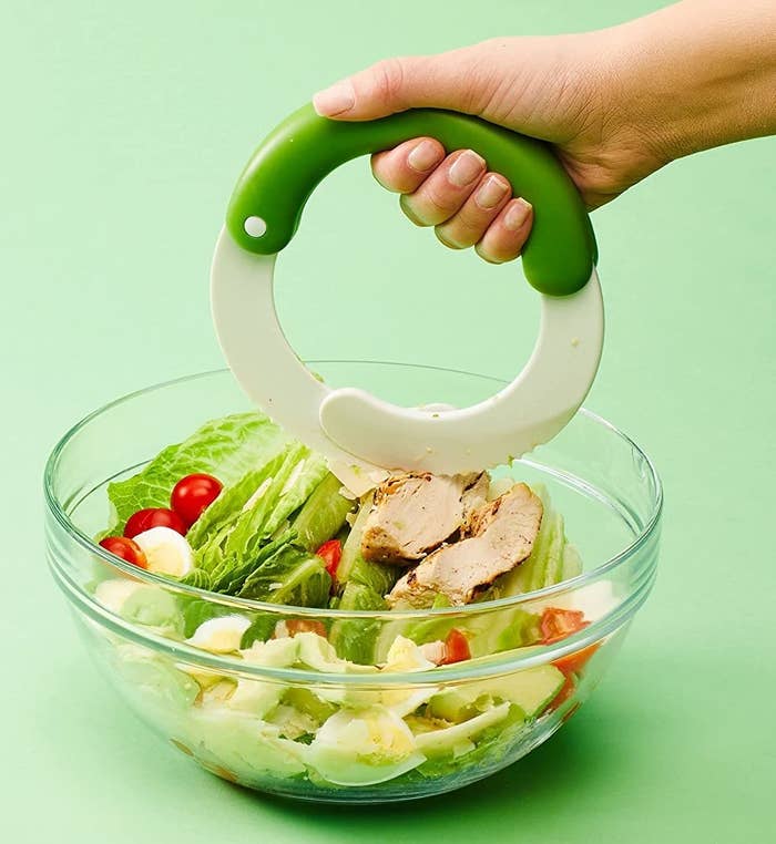 A person using the blade to cut up a salad