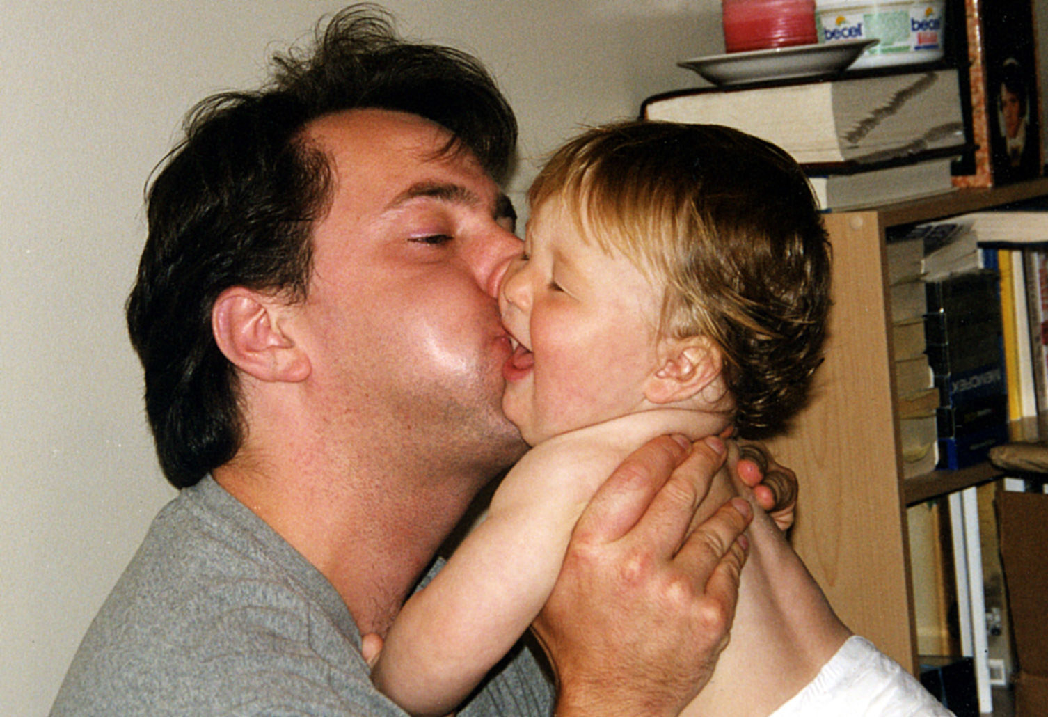 一个男人亲吻他年幼的儿子的脸颊
