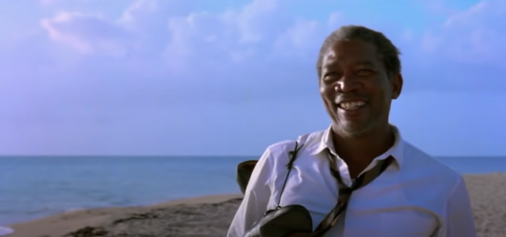 A man, smiling, walks on a beach