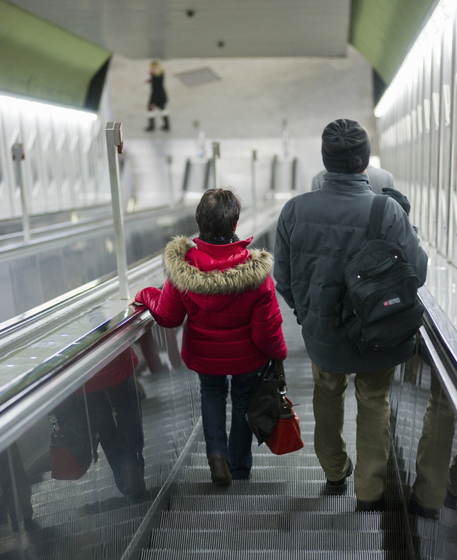 two people on a down escalator