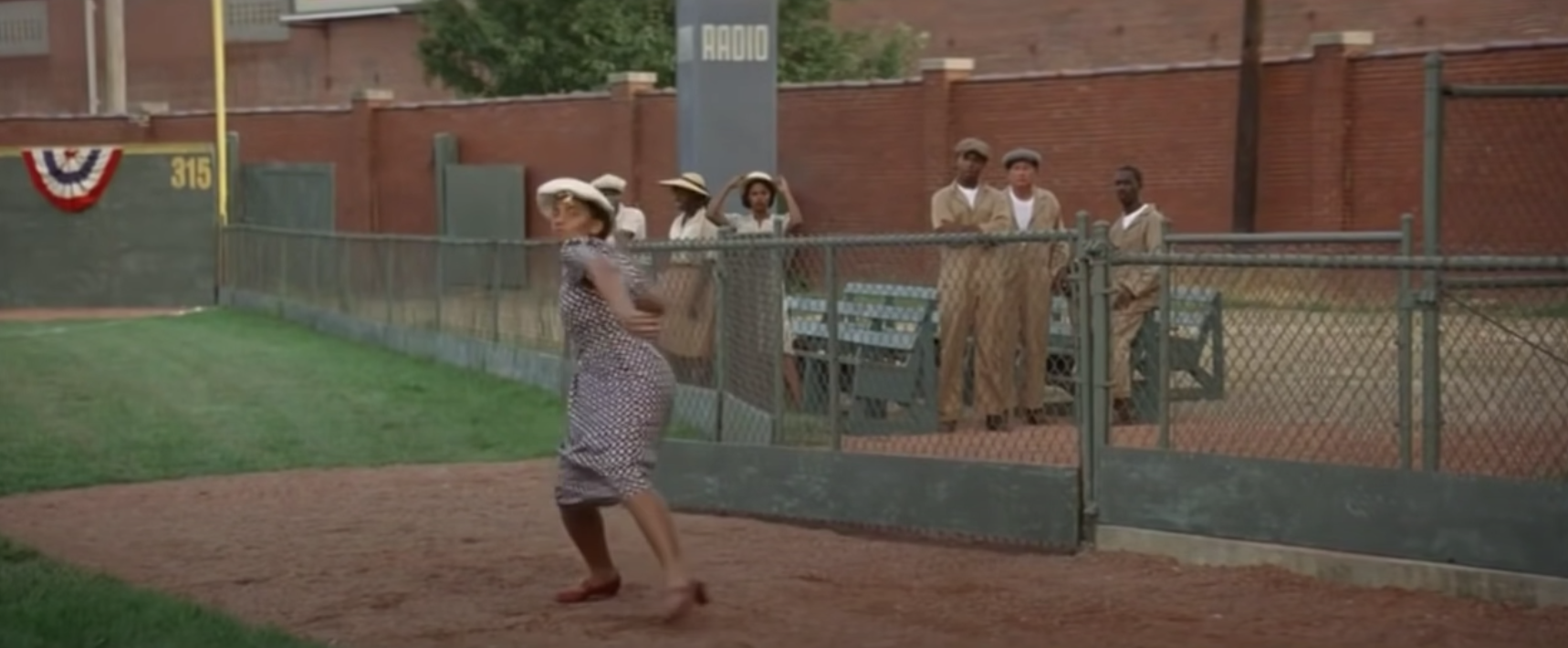A woman throws a ball by a fence