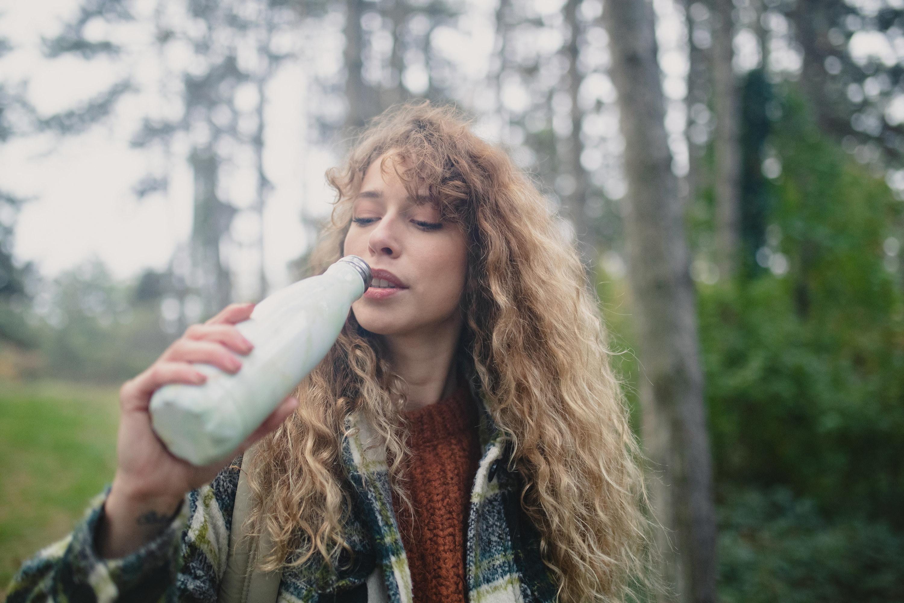 Hiking woman drinks water from a reusable bottle