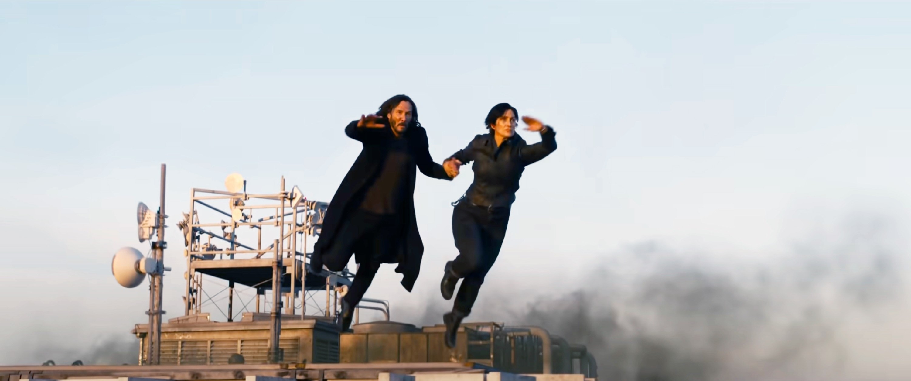 Keanu Reeves and Carrie-Anne Moss dive from the roof of a building