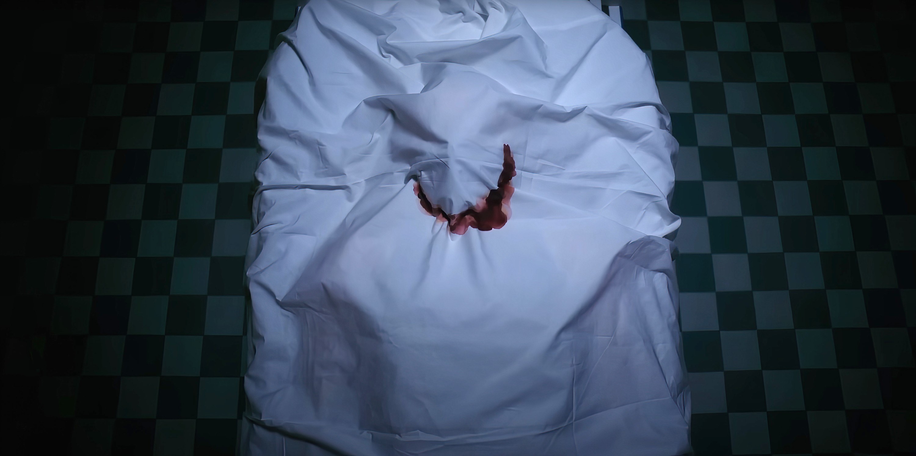 A dead body with a sheet pulled over, bleeding in the shape of a smile