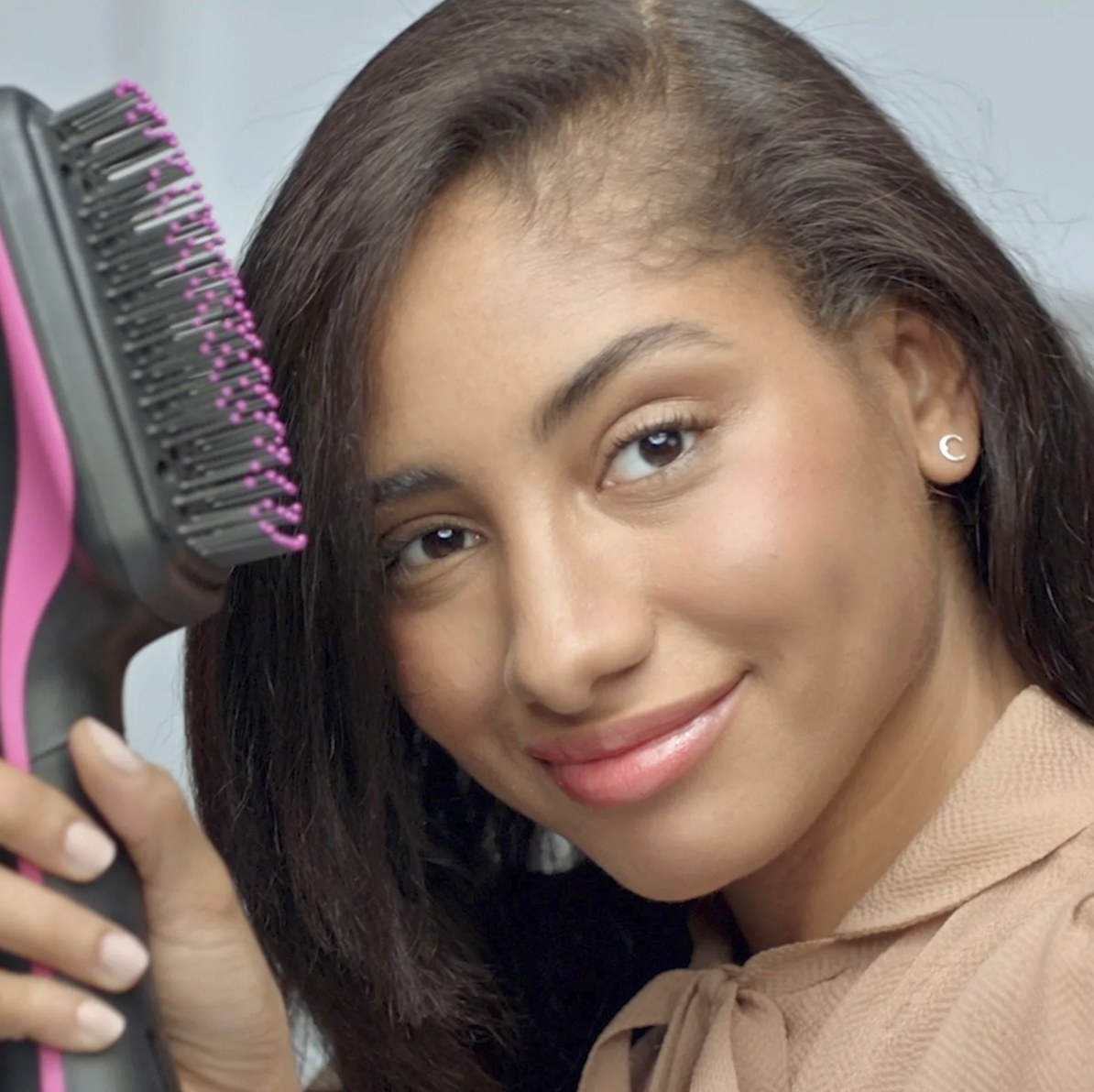 a model holding the hairbrush-style hair dryer