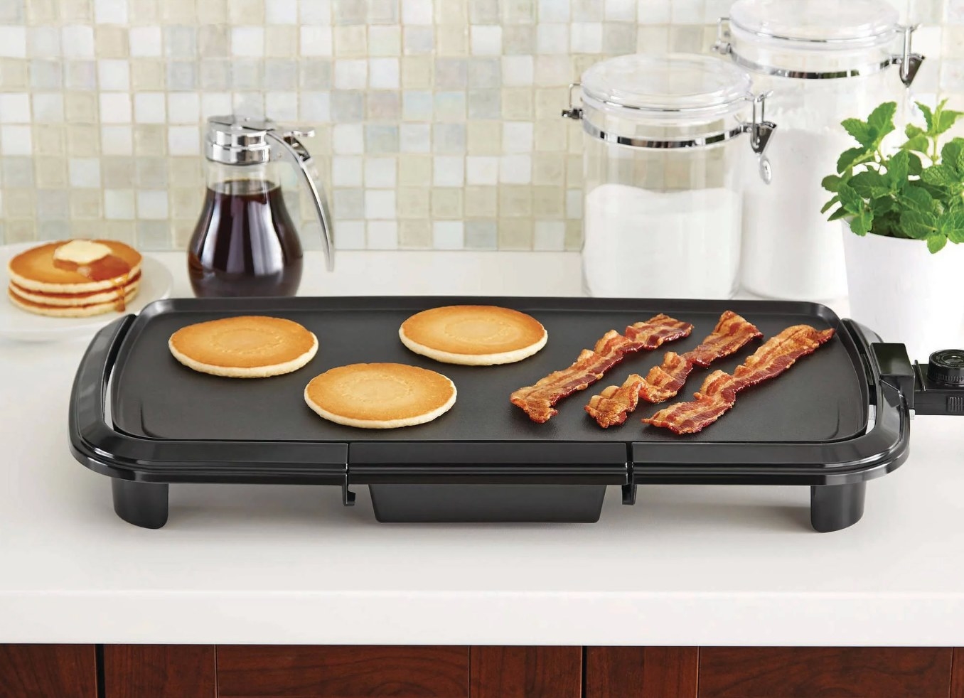 the black griddle with pancakes and bacon on a decorated kitchen counter
