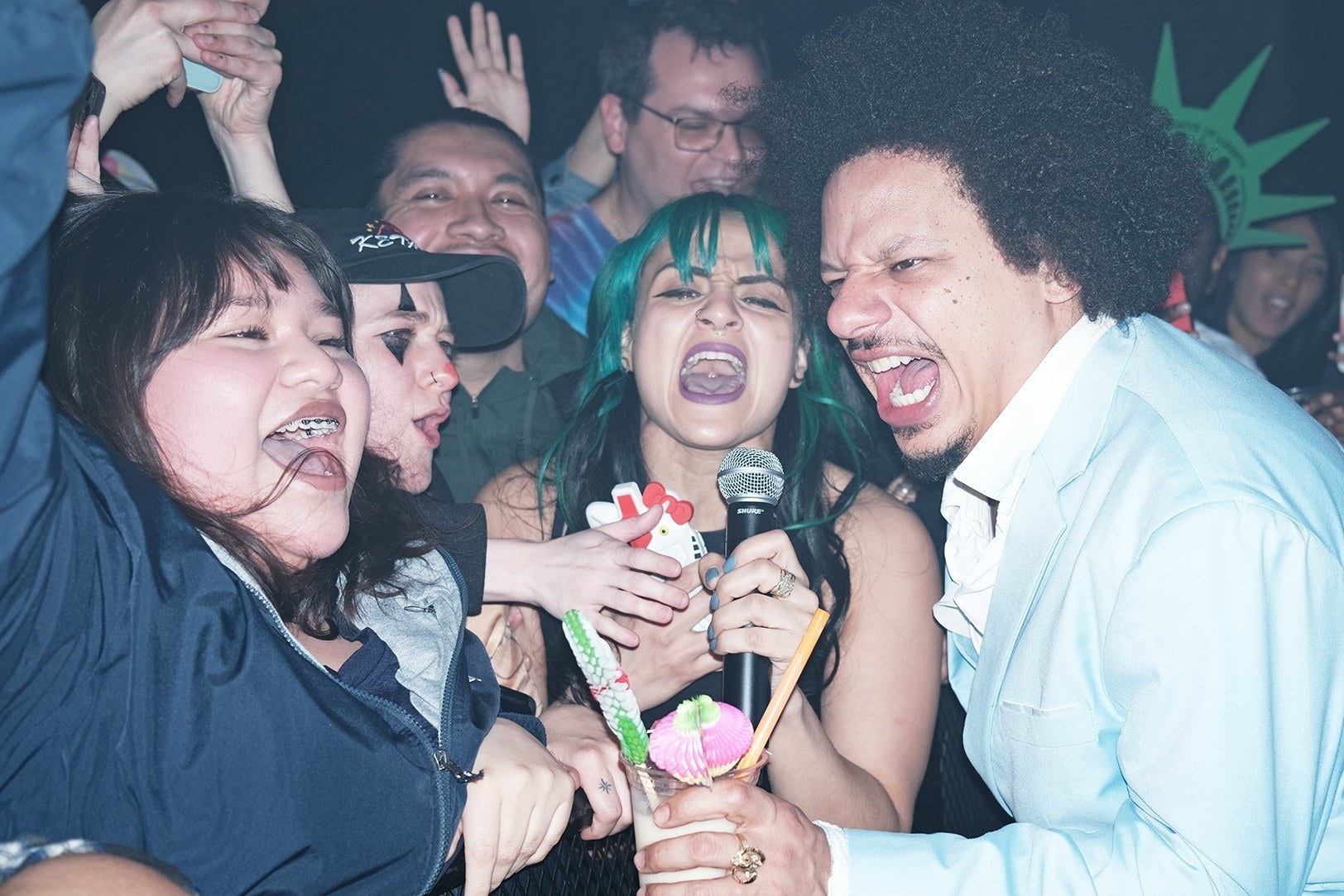 Eric André and several partygoers yell into a microphone