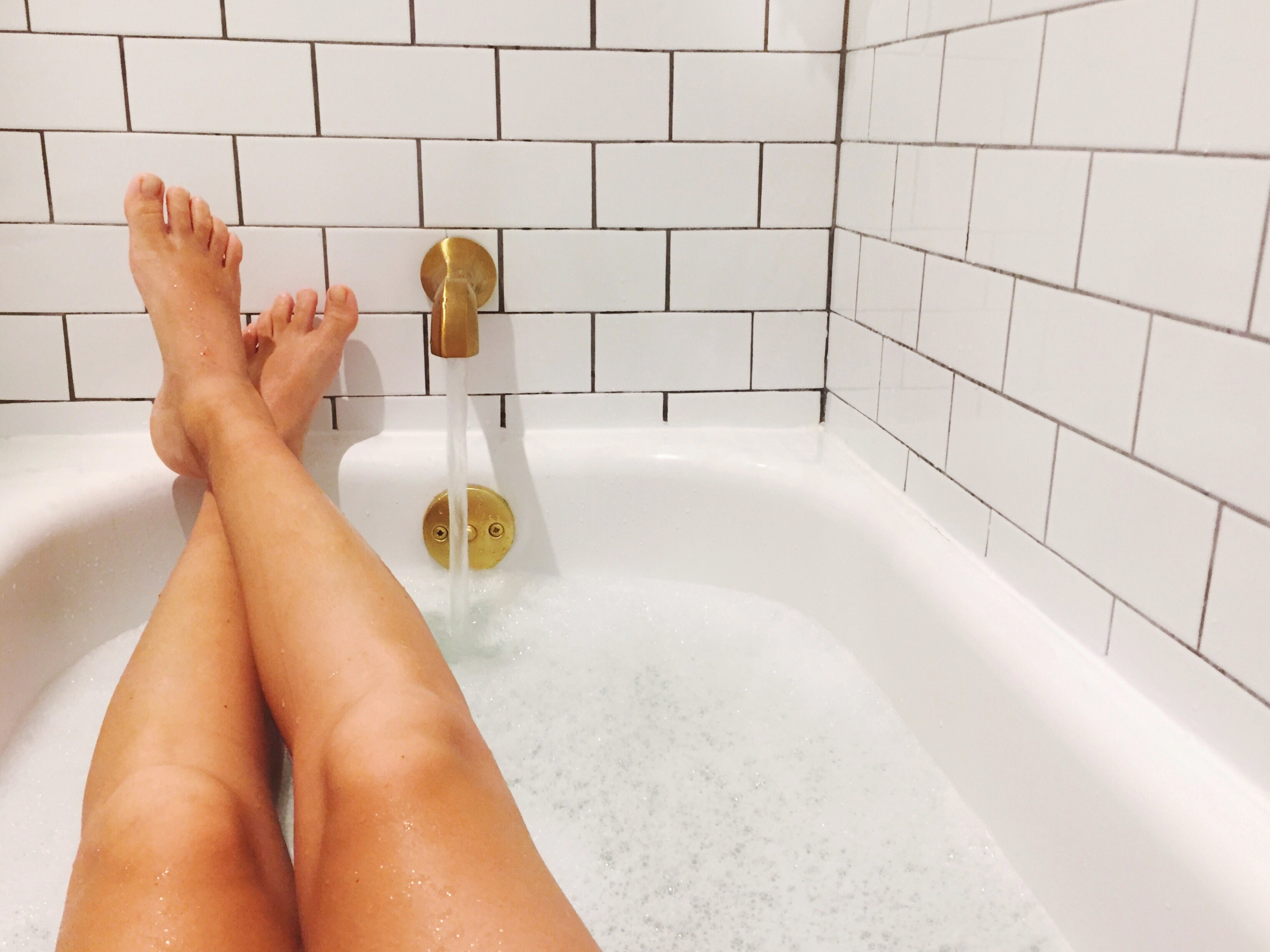 A woman&#x27;s feet in a bath tub.