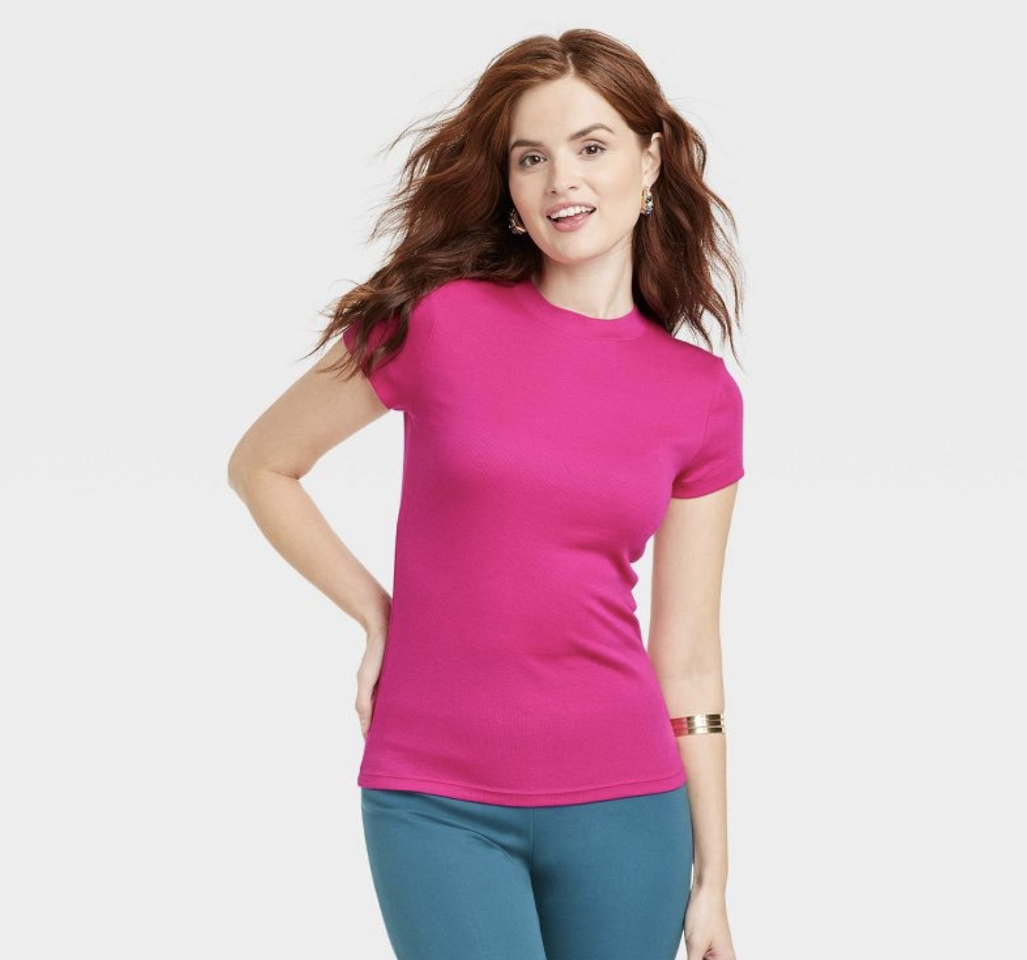 A person with long red hair wearing a hot pink shirt