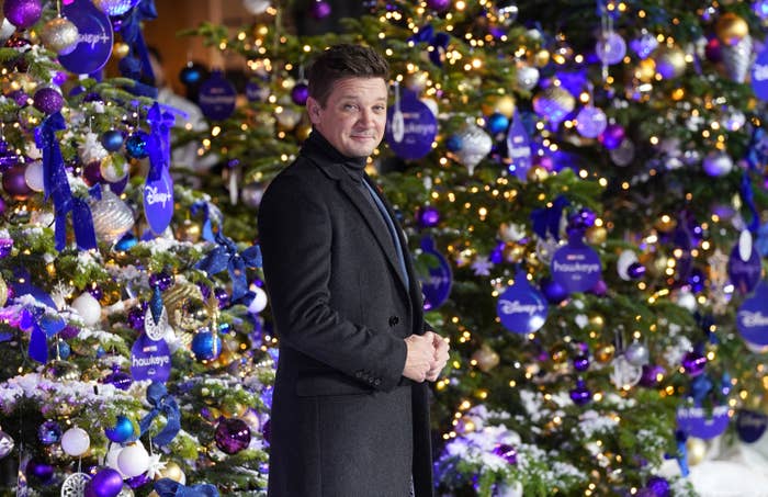Jeremy standing in front of decorated Christmas trees at the premiere of Hawkeye