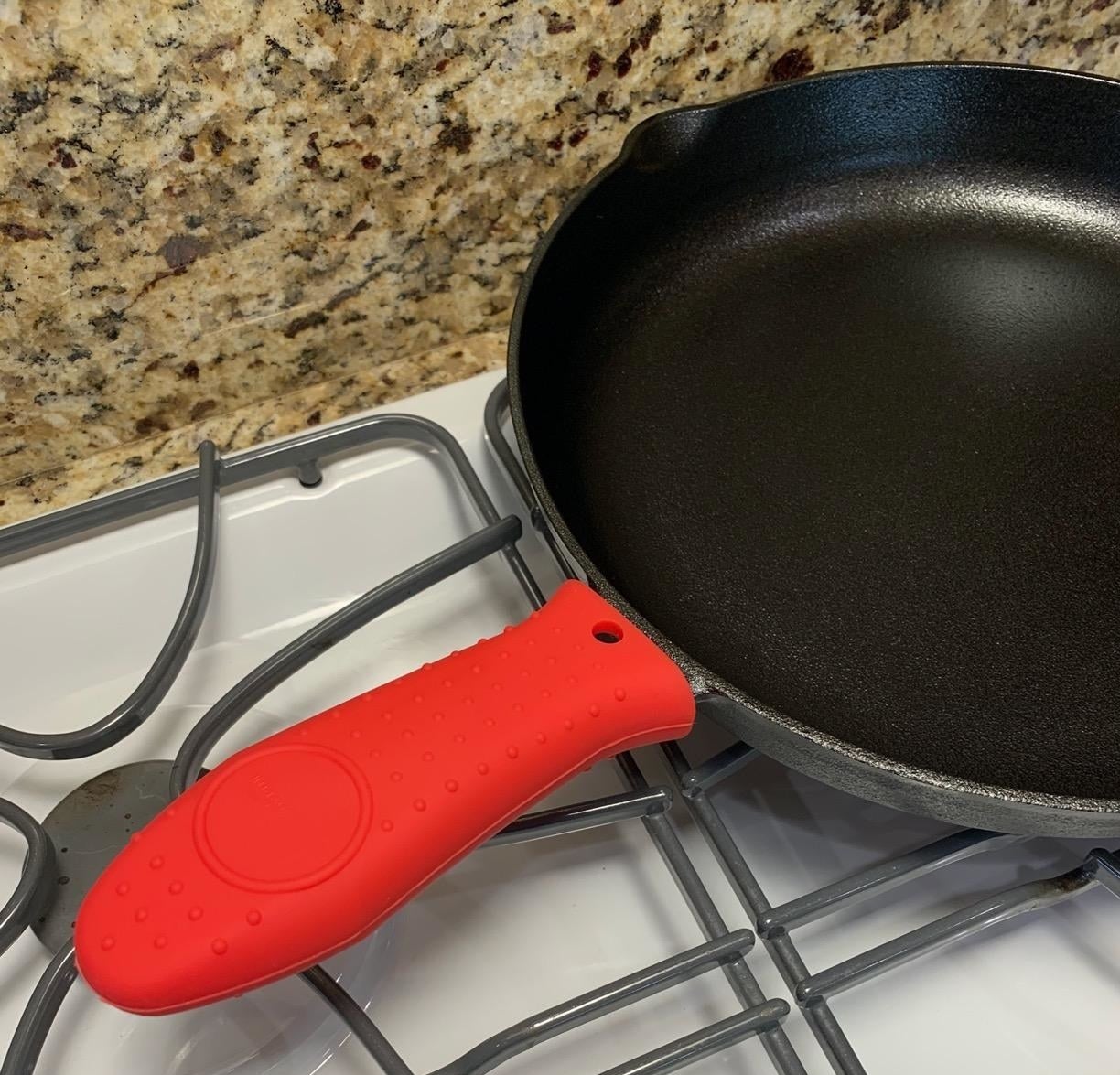 Reviewer image of the red silicone handle on a cast iron skillet