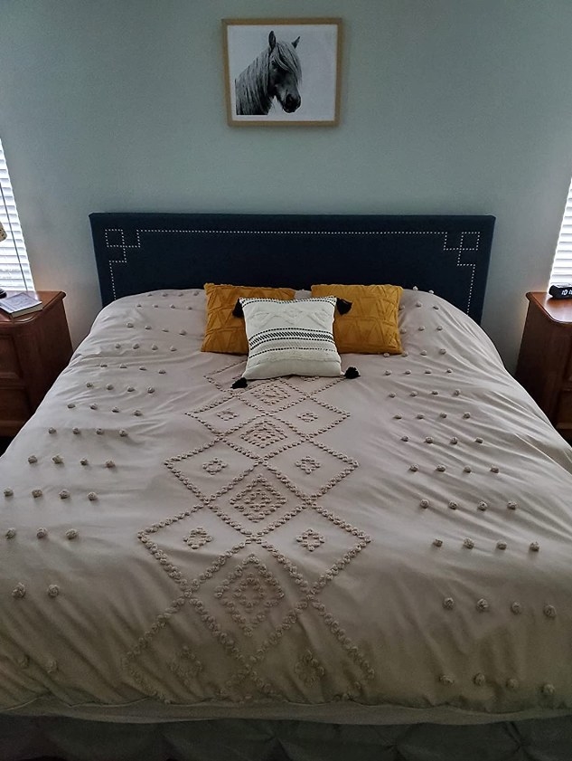 A reviewer&#x27;s photo of the tufted bedding set on the bed
