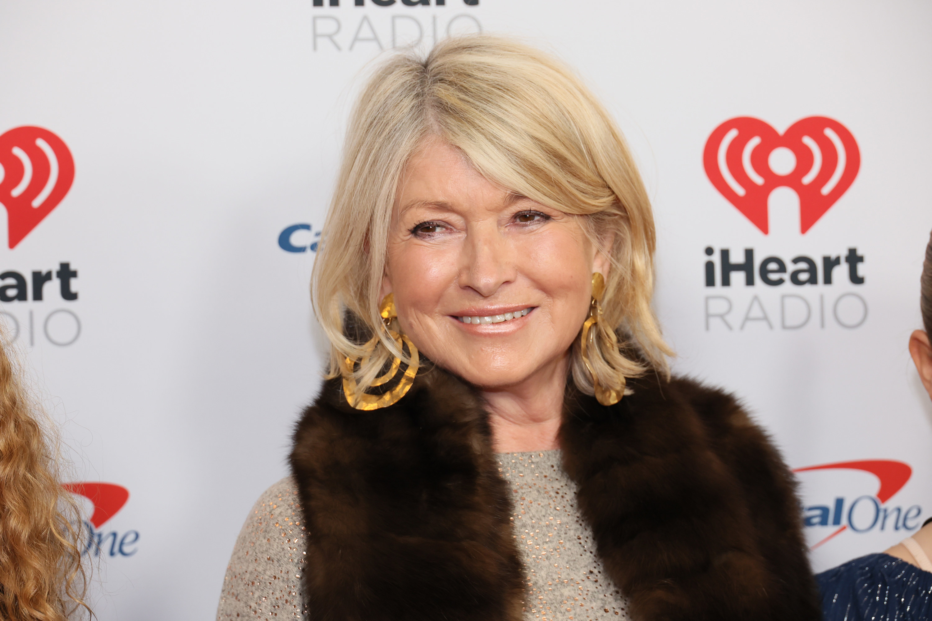Martha Stewart, wearing a furry vest, brown shirt, and gold earrings, on the red carpet