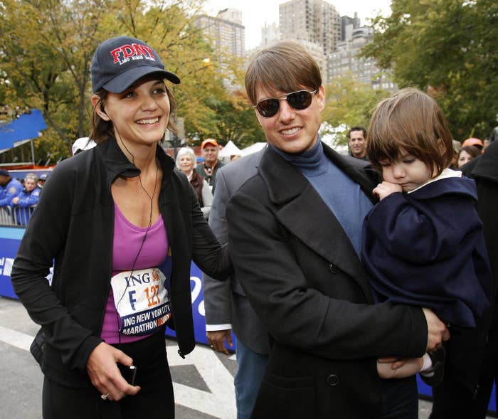 Tom holding a toddler Suri and welcoming Kate after she finished the New York City Marathon