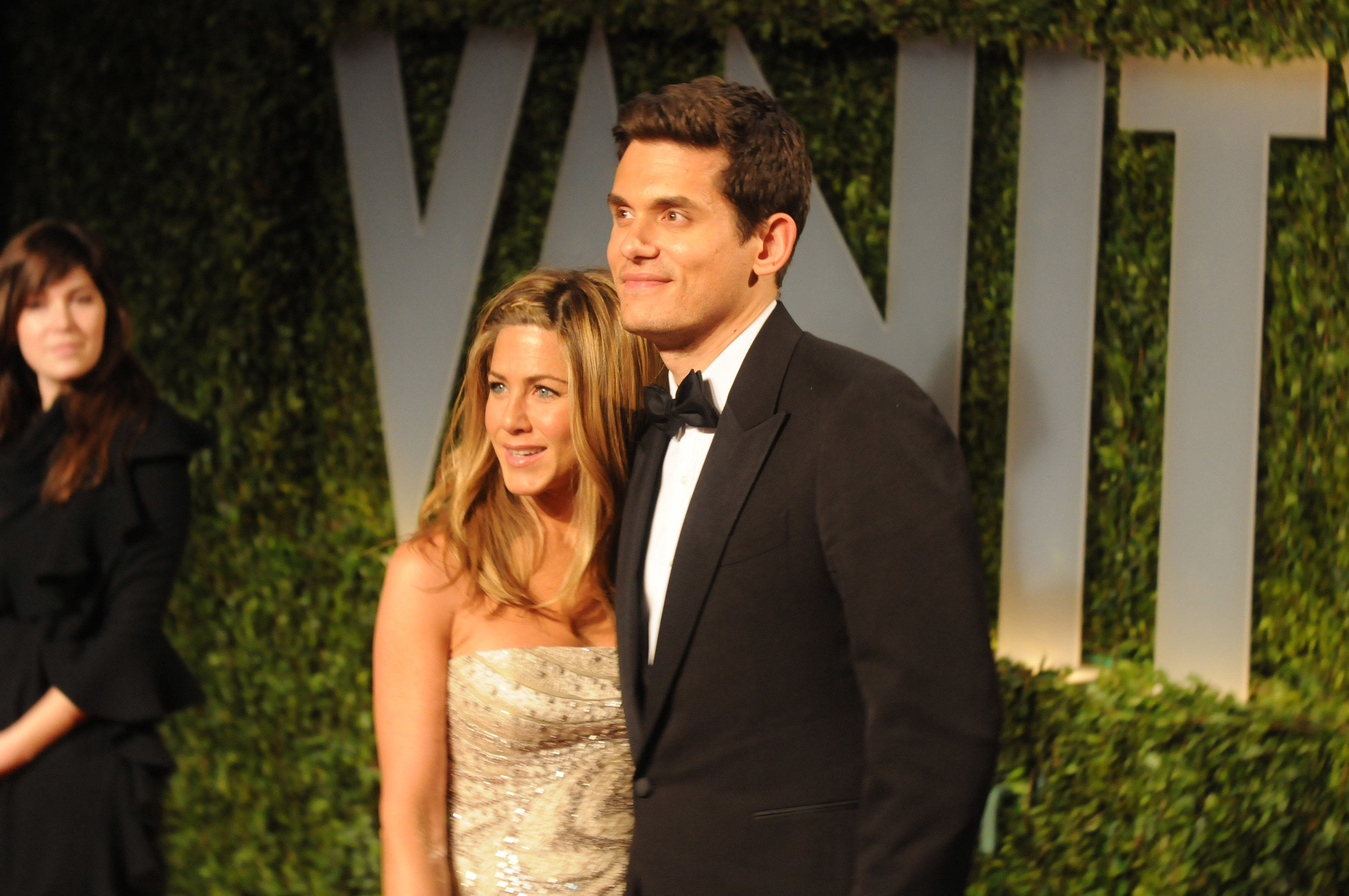 John Mayer and Jennifer Aniston in black tie clothing post arm in arm on the red carpet