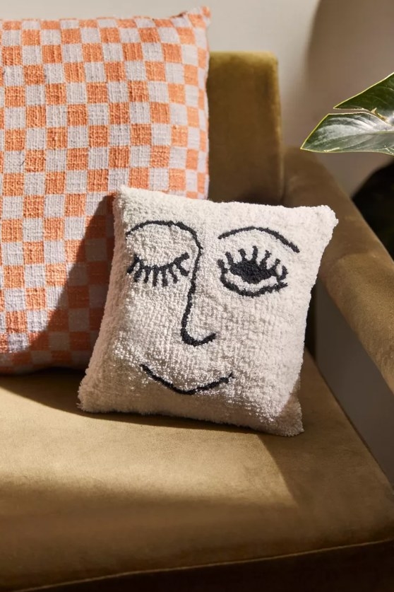 The winky face throw pillow on a chair