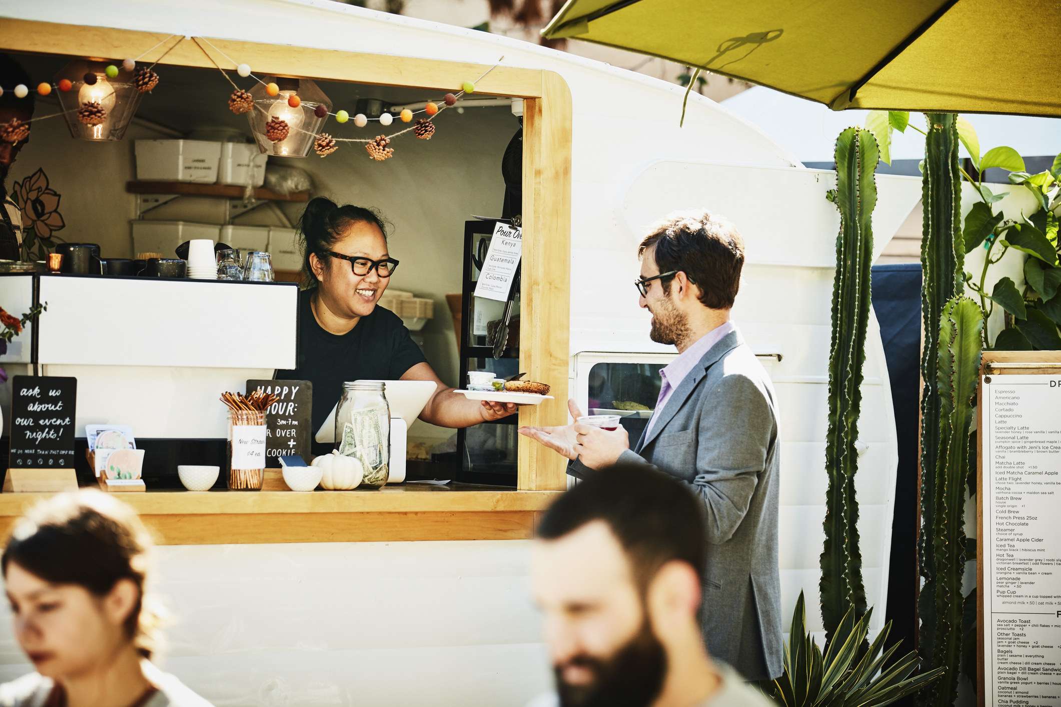 A woman handing a customer their food at a restaurant