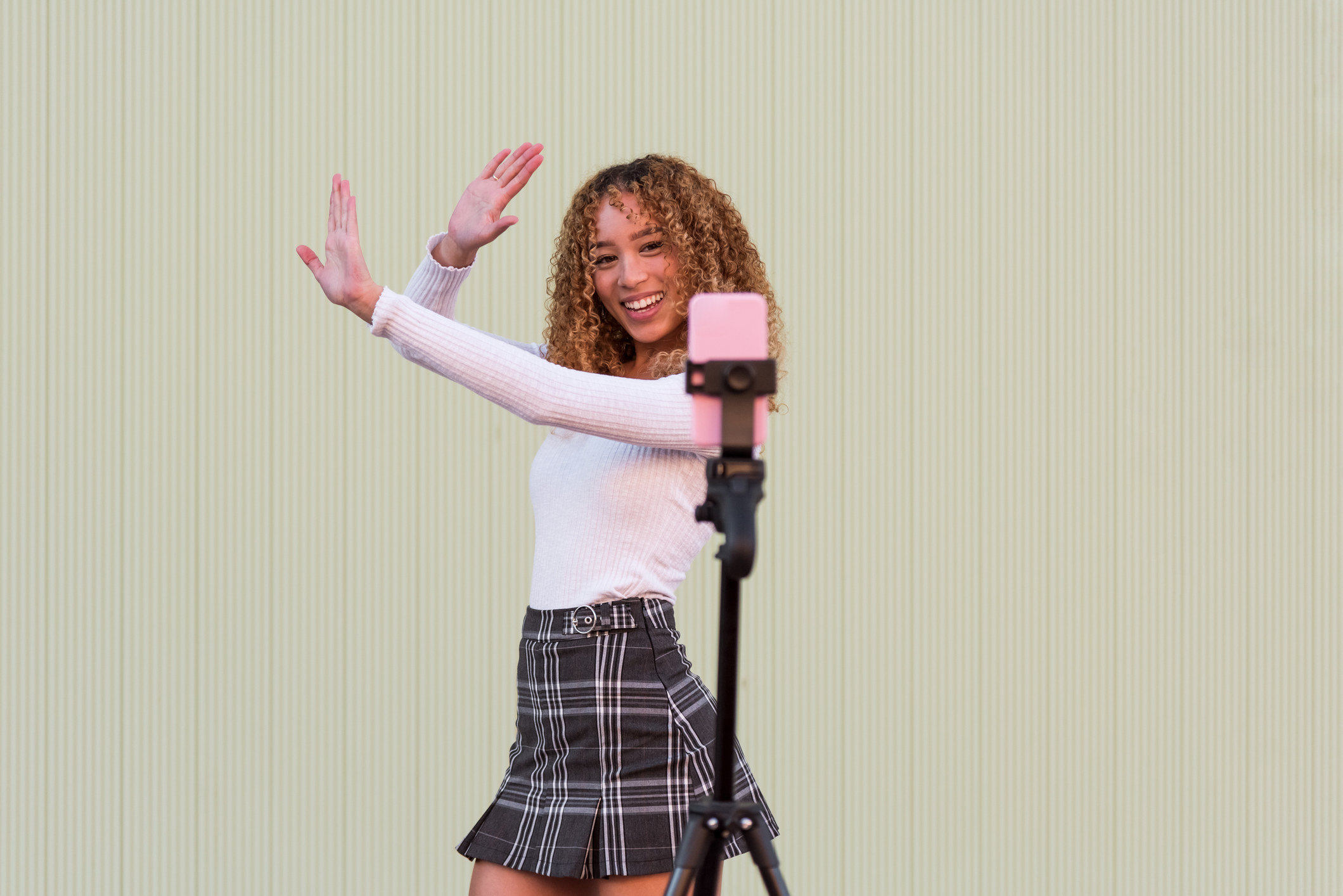 A young woman dancing in front of her phone on a tripod