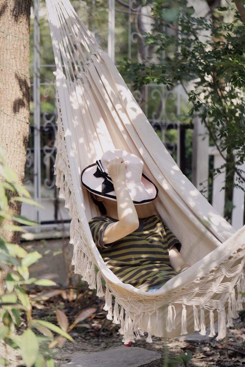 person lying on the hammock with a hat covering their face