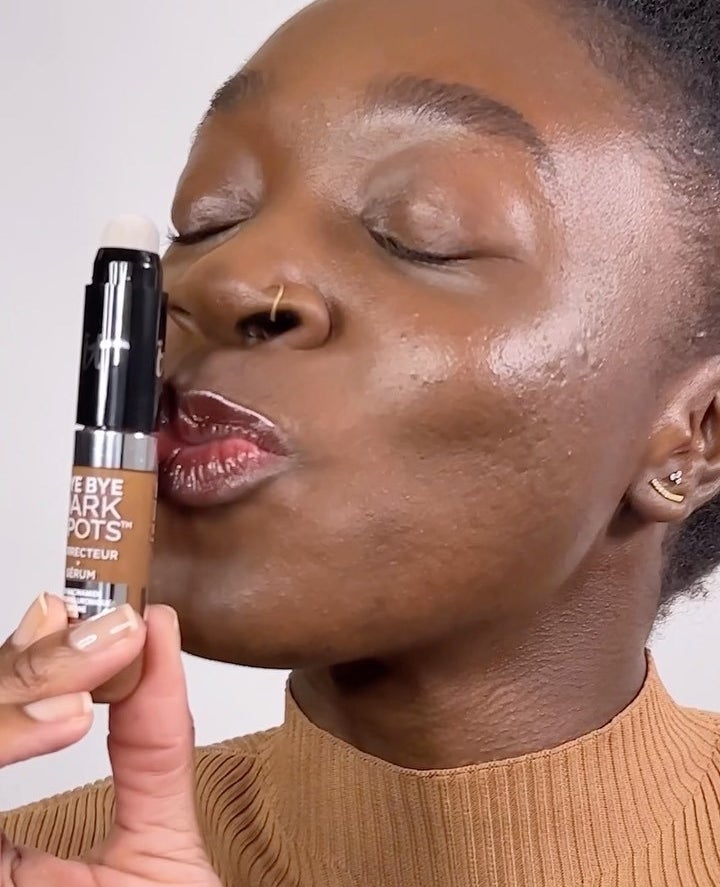 someone kissing a tube of the concealer serum