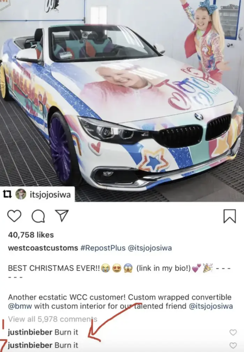 A screenshot of an Instagram post where Jojo Siwa is posing in front of a very brightly colored car that has her face and name on the hood, there are two comments from Justin Bieber reading &#x27;Burn it&#x27;