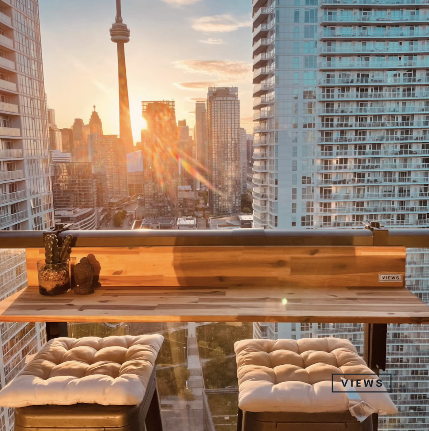 the table on a glass balcony with two stools and a view of the CN tower