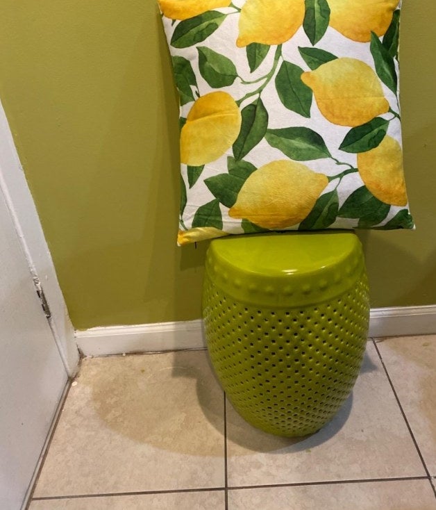 The lemon printed throw pillow cover on display on a stool