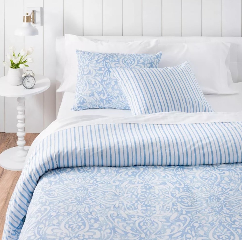 white and blue medallion comforter with white sheets and matching pillowcases on bed