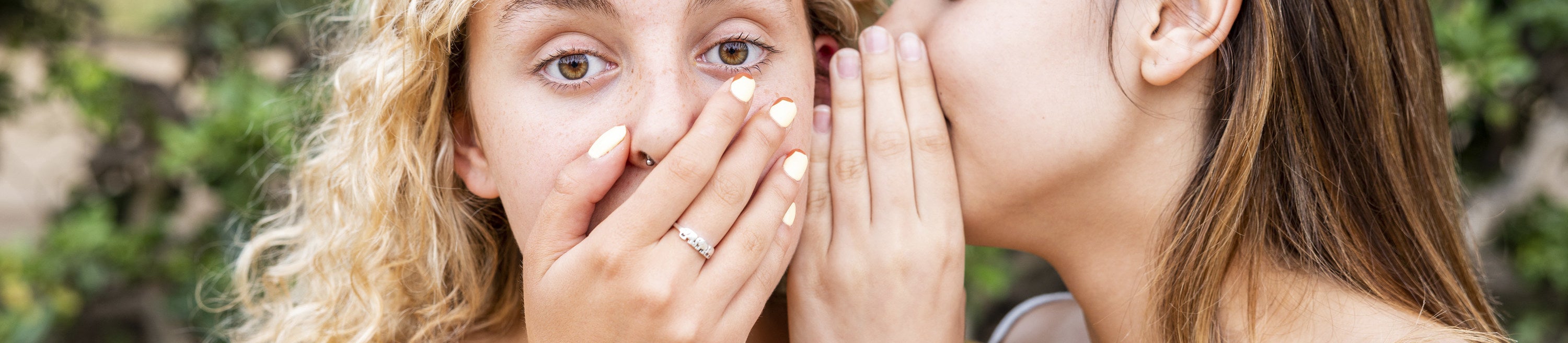 woman whispering in another's ear