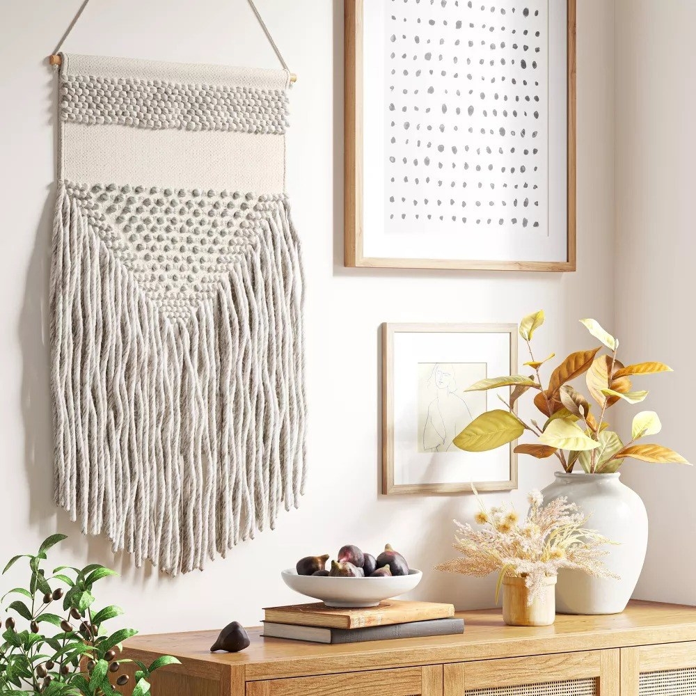 the off white woven wall hanging on a wall