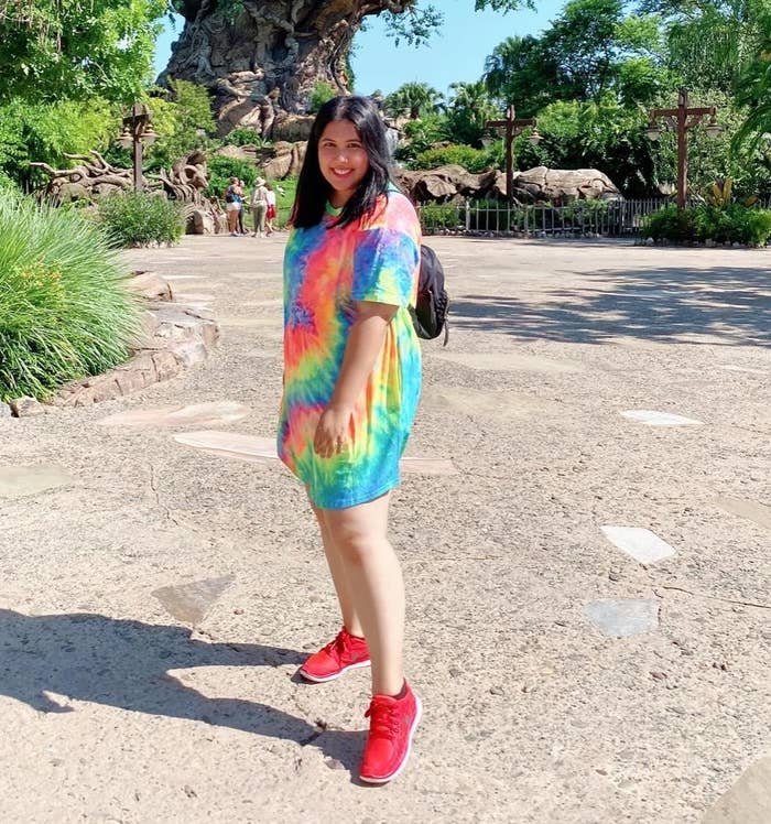 Reviewer wearing rainbow colored tie-dye t-shirt dress with red sneakers