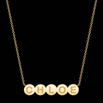 a dainty gold necklace with gold bubbles as a nameplate that say 