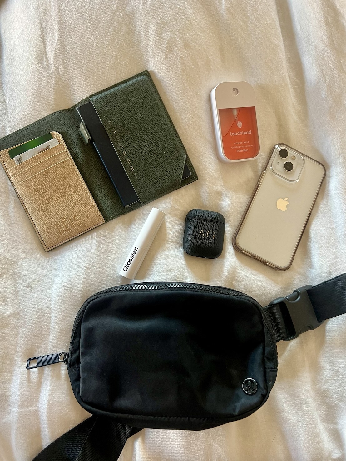 image of a black fanny pack with essentials around it