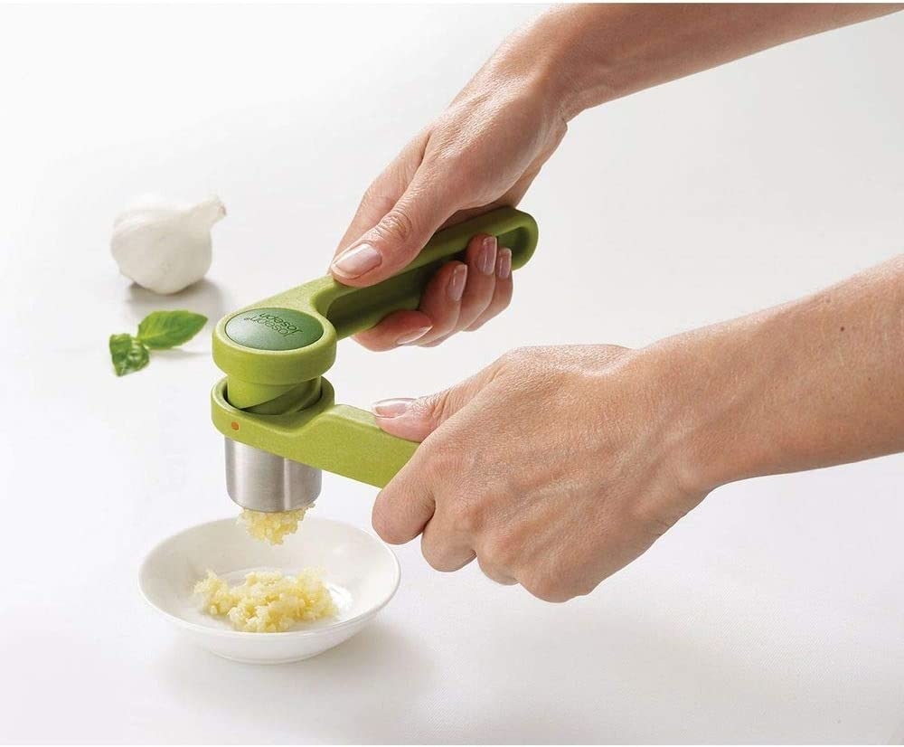 A pair of hands using the garlic press