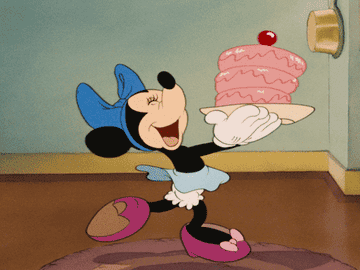 a gif of minnie mouse skipping while holding a teetering cake