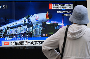 A woman watches street TV broadcasting breaking news of a North Korean missile launch in Tokyo