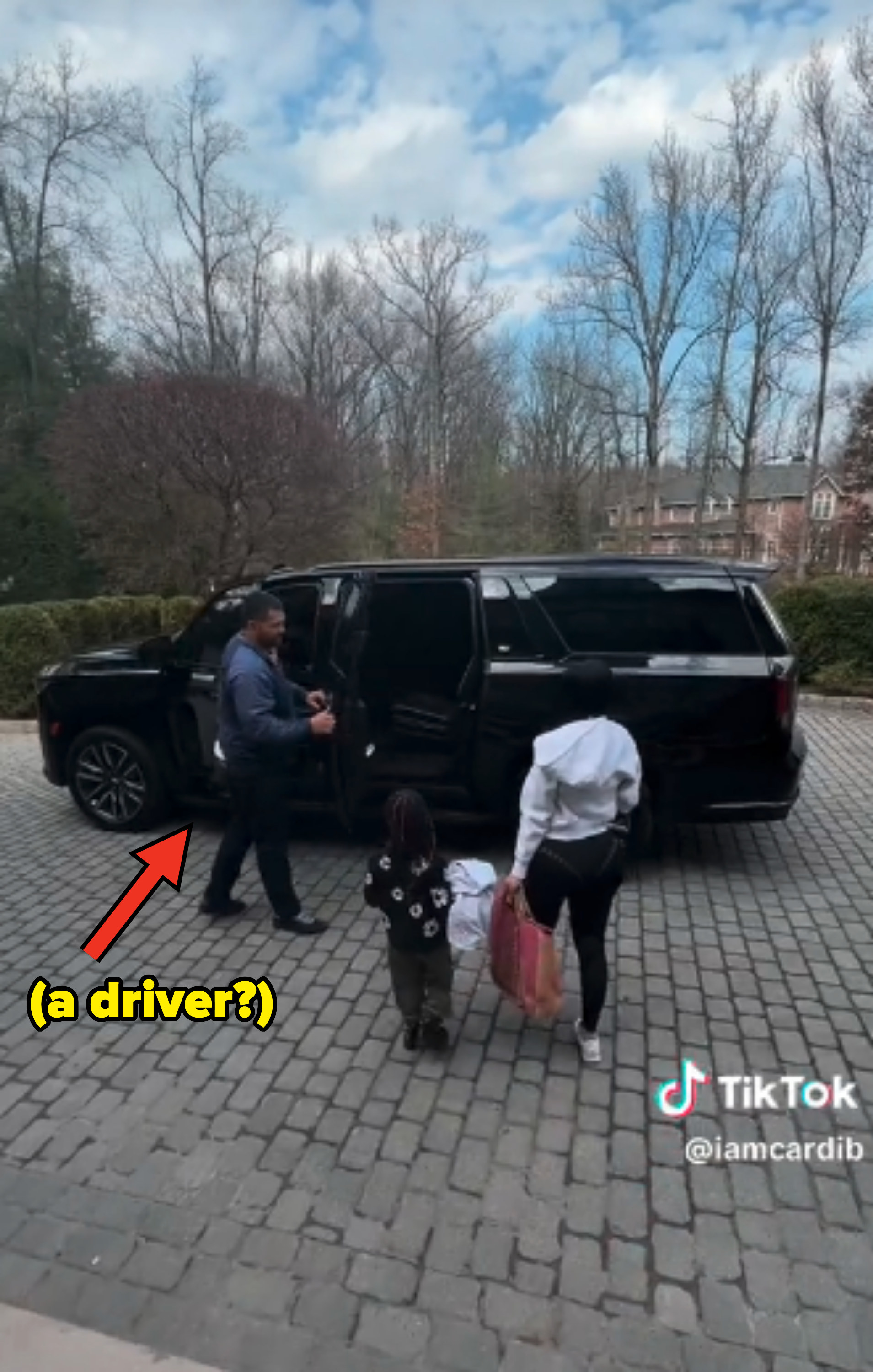 As Cardi approaches an SUV with her child next to her, an arrow points out that she has a personal driver