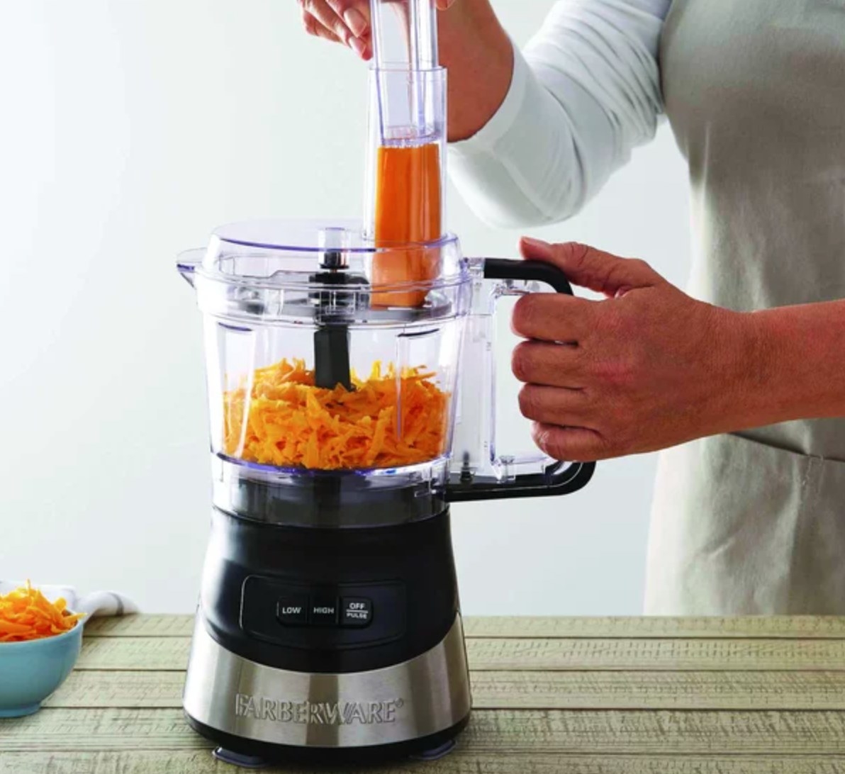 a model using the small food processor to shred a block of cheese