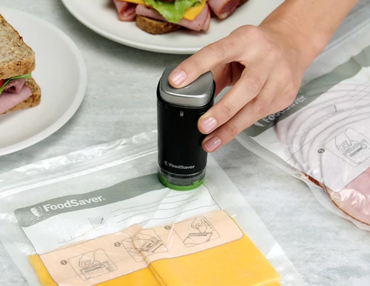 a model using the small black vacuum sealer to remove air from bags of deli meats and cheeses