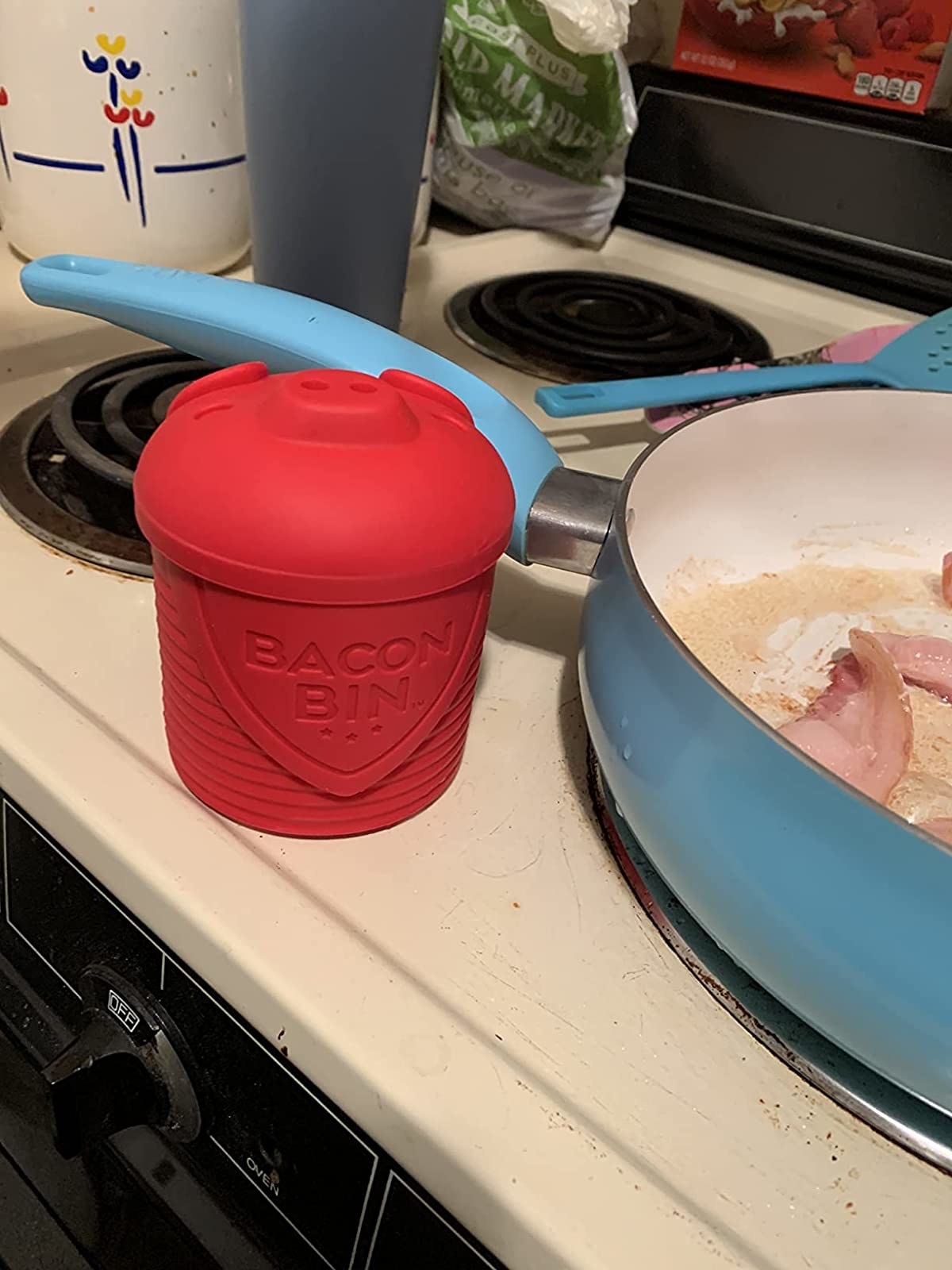 reviewer showing the bacon bin on a stove