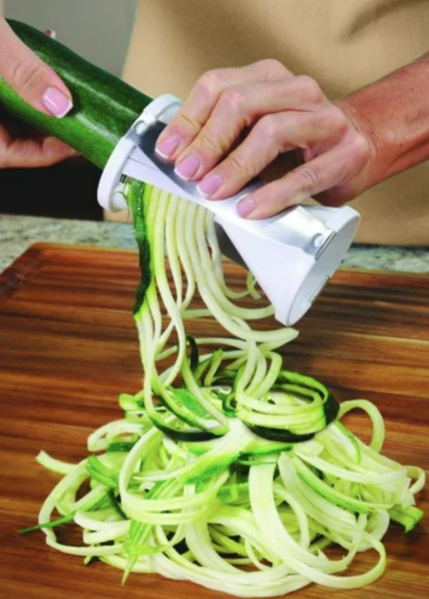 a model using the white spiralizer to cut a zucchini into ribbons