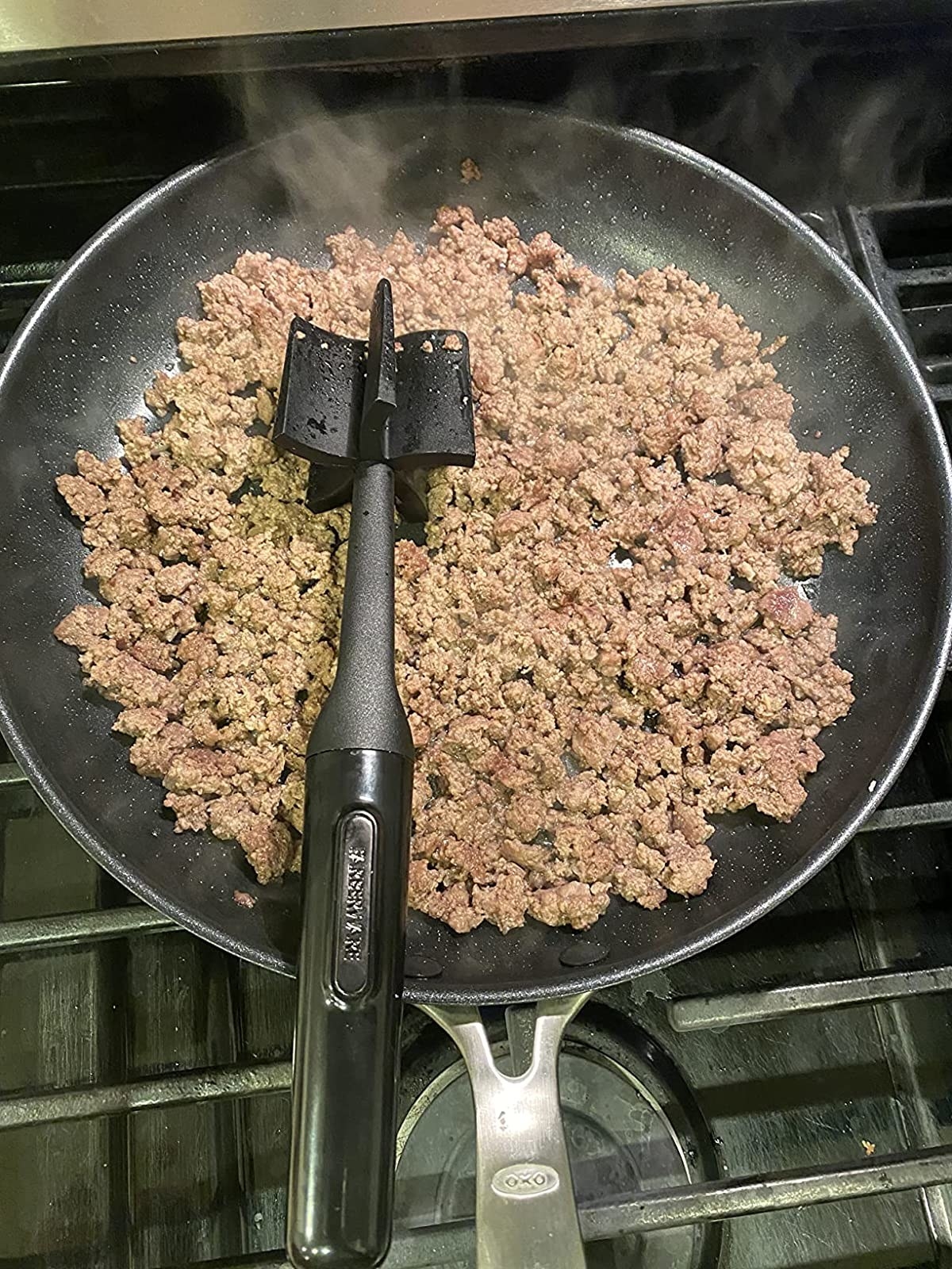 reviewer using the meat masher in the pan