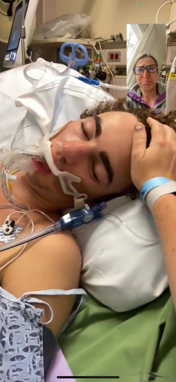 A young man in a hospital bed is hooked up to a breathing apparatus