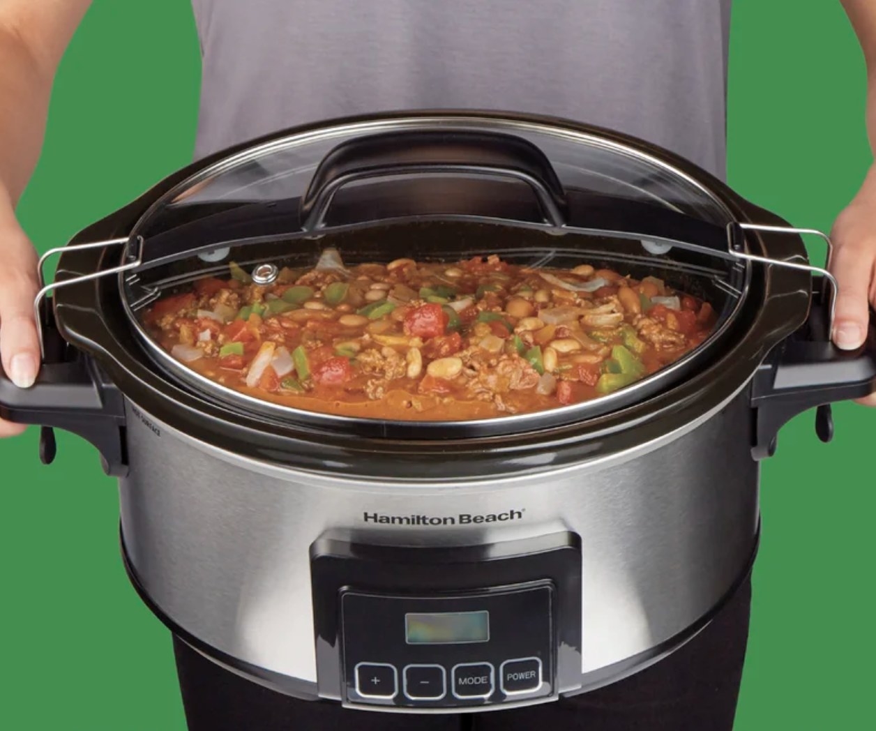 A model holding a crockpot with vegetable stew inside